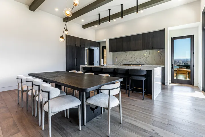 Open-concept kitchen and dining area featuring wood-finish flooring and exposed ceiling beams