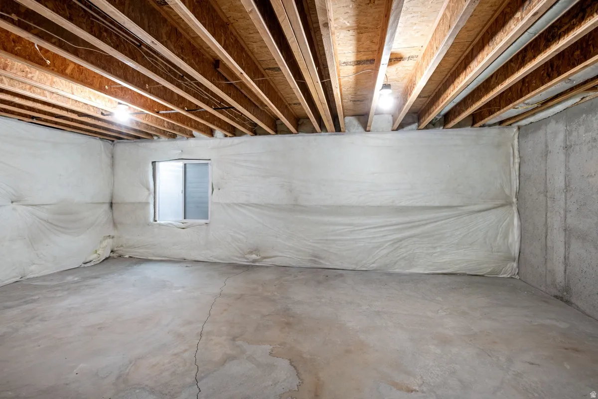 Unfinished basement offering exposed wood ceiling joists and concrete flooring