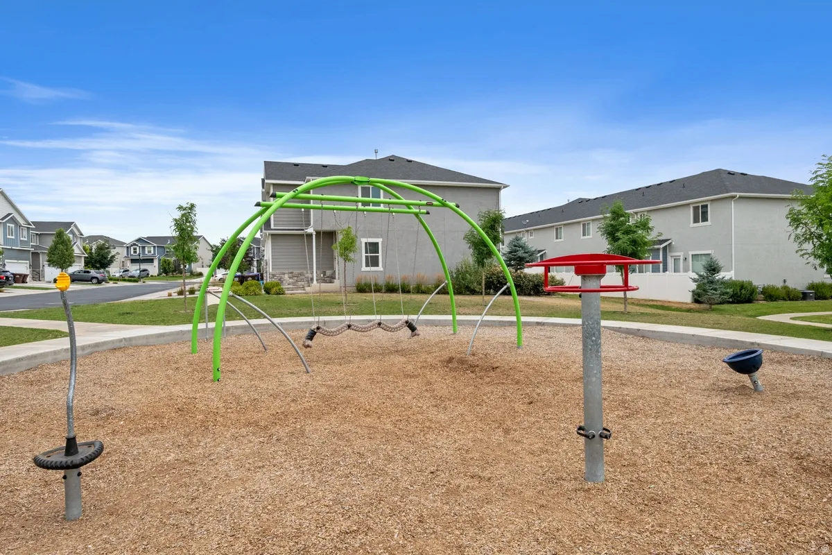 Community playground featuring wood chip surfacing, a green arch swing set, and a red spinning play structure