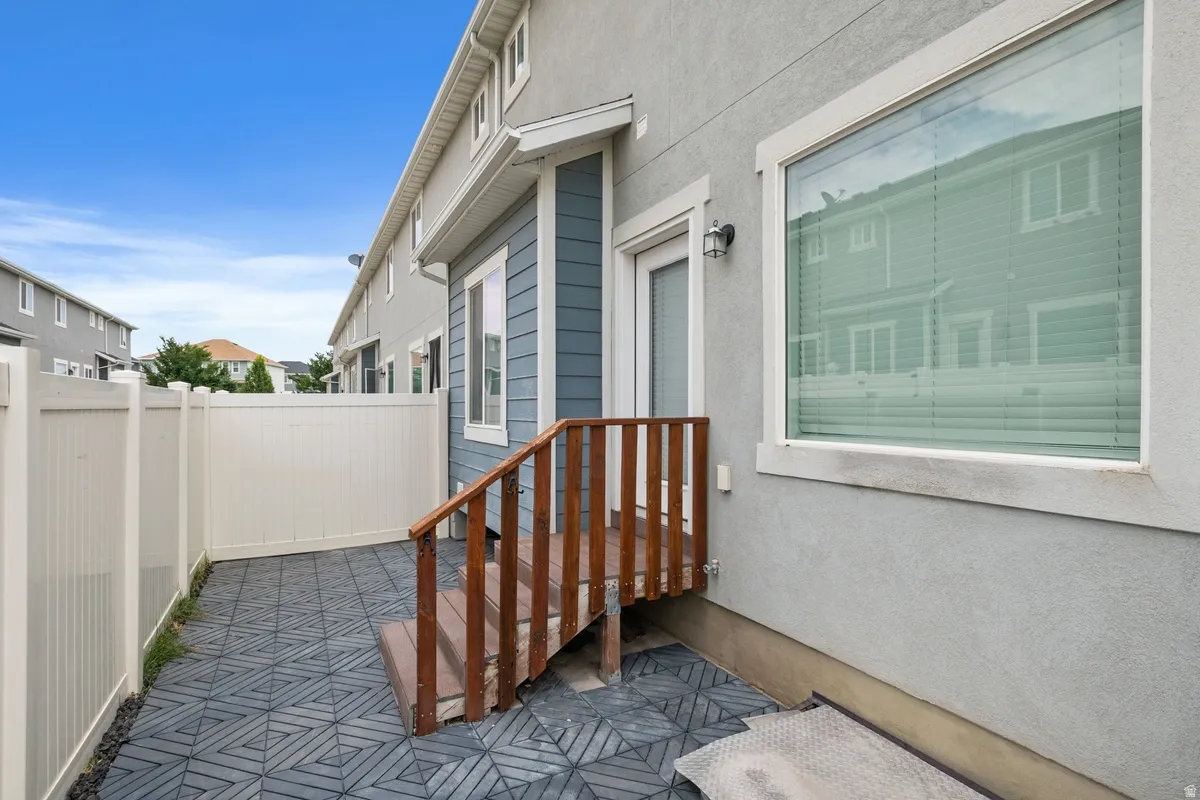 Private patio featuring dark gray interlocking pavers, white vinyl fencing, and a wooden staircase
