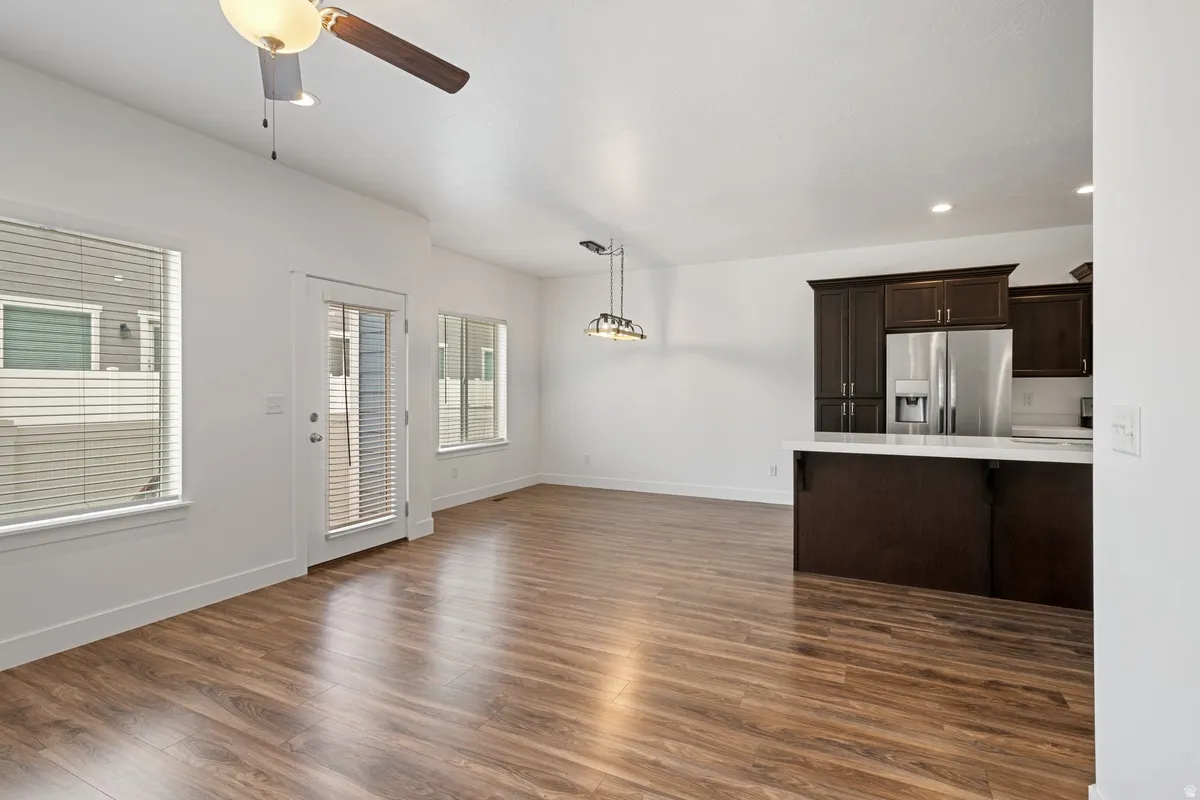 Open-concept living area featuring wood-finish flooring, white walls, and a ceiling fan