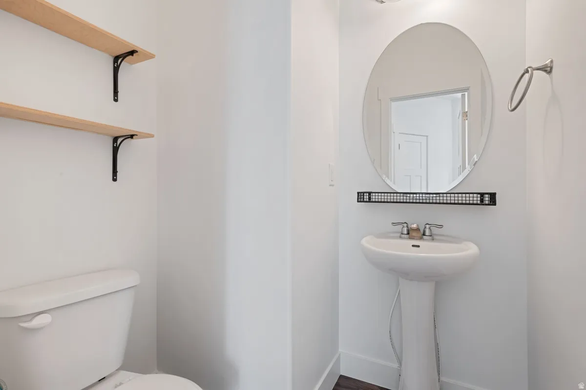 White pedestal sink with dual-handle faucet and oval wall mirror