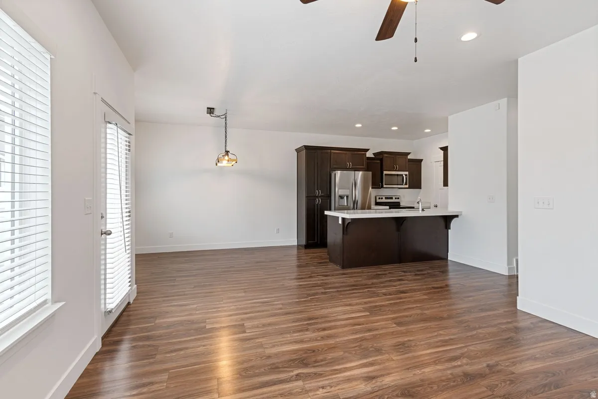 Open-concept living area featuring wood-finish flooring, white walls, and a modern kitchen