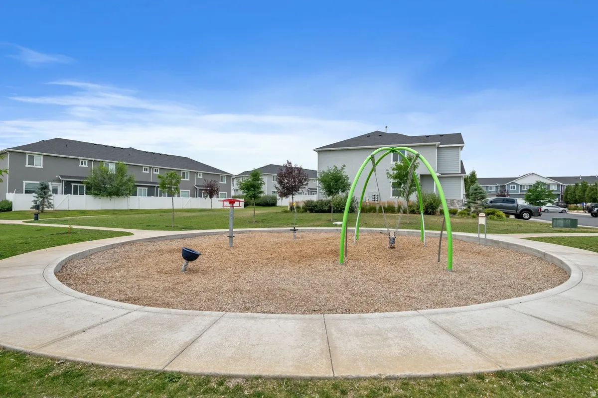 Community park with a circular concrete path, playground equipment, and wood chip surfacing