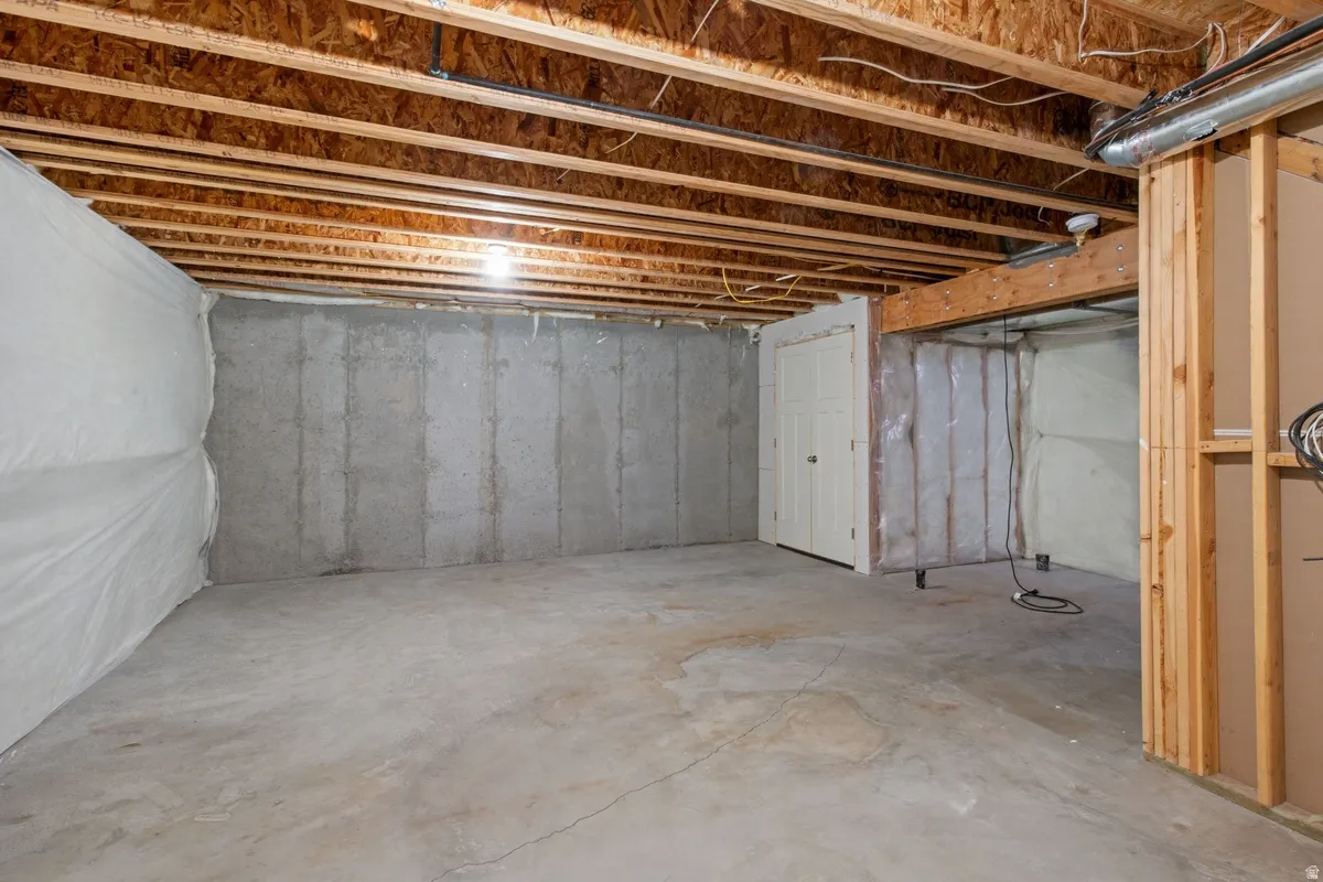 Unfinished basement featuring exposed wood joists and concrete flooring