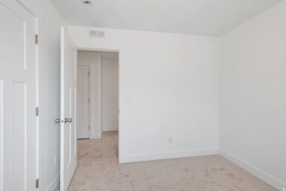 Interior room featuring plush carpet flooring, white walls, white trim, and white doors with satin nickel hardware