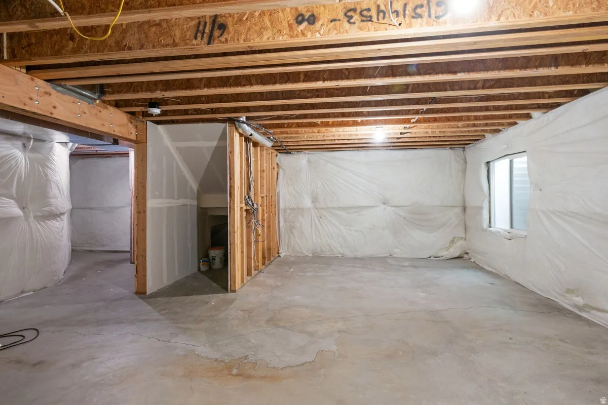 Unfinished basement space featuring exposed wood joists and concrete flooring