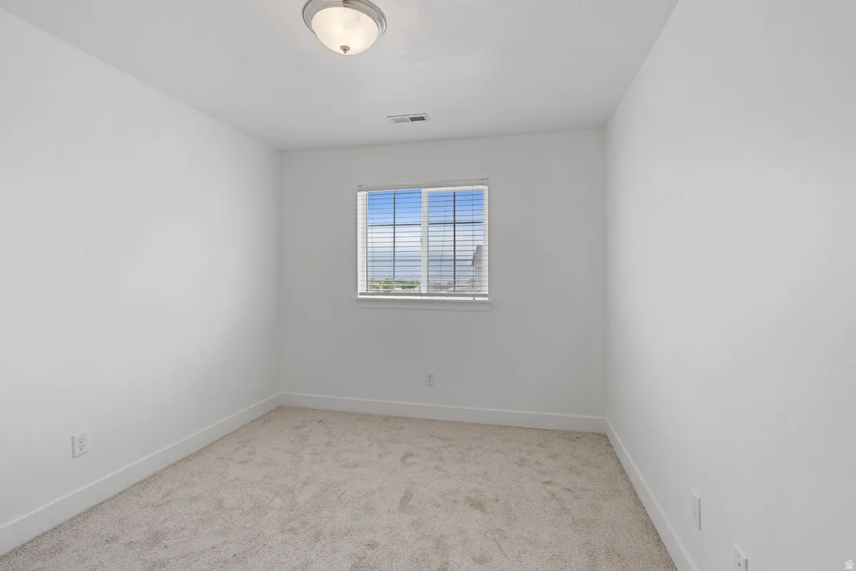 Carpeted room featuring a single window with horizontal blinds, a white ceiling with a flush-mount light fixture, and white baseboards