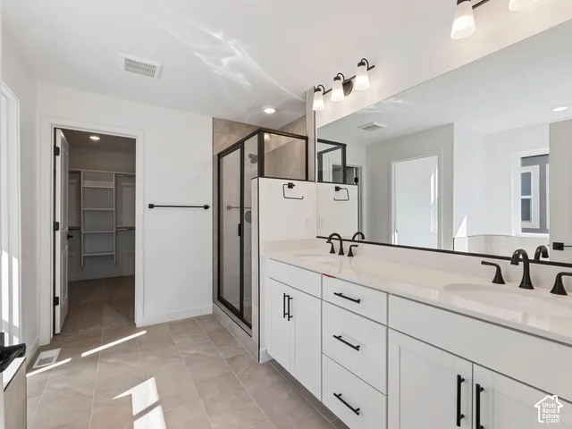 Double vanity with white cabinetry and matte black hardware, dual sinks, and a large wall-mounted mirror