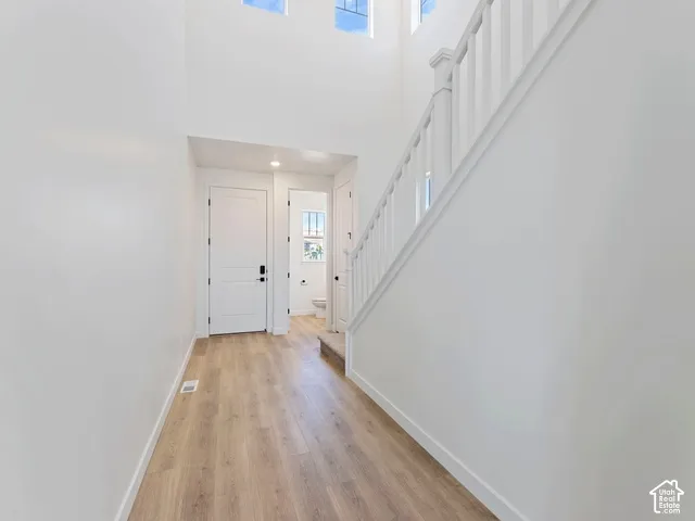 Two-story entry with wood-finish flooring, white walls, and a white staircase with banister