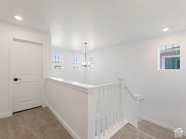 Loft area featuring recessed lighting, multiple windows, a white balustrade, and a contemporary chandelier