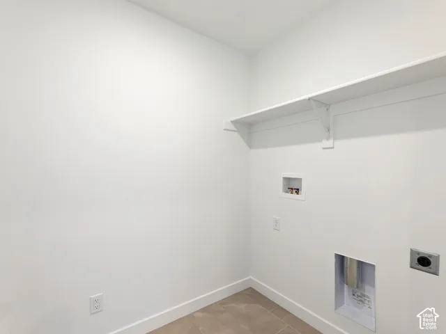 Dedicated laundry area with a white wall shelf, utility hookups, and tiled flooring