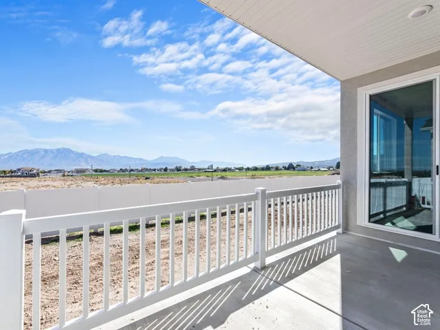 Patio featuring a concrete surface, white railing, sliding glass door, and distant mountain scenery