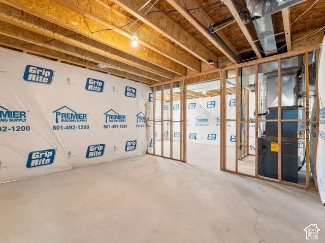 Unfinished basement with exposed wood framing, concrete flooring, and visible ductwork