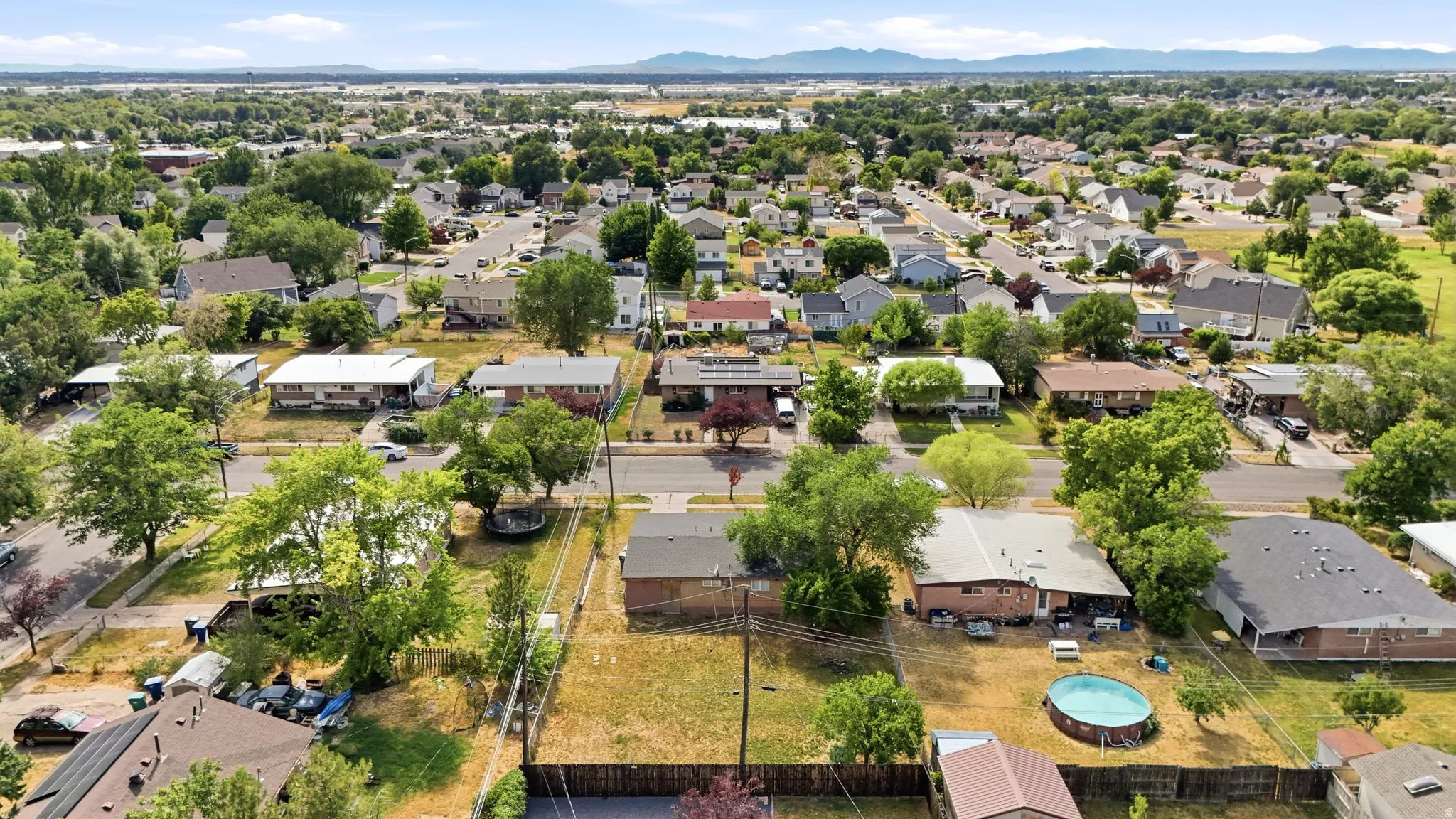 Expansive residential neighborhood featuring numerous single-family homes, mature trees, and mountainous terrain in the distance