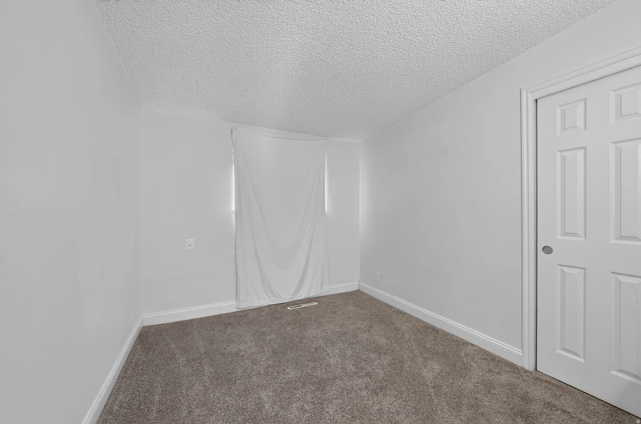 Neutral-toned wall-to-wall carpeting, white painted walls, and white baseboards create a clean interior