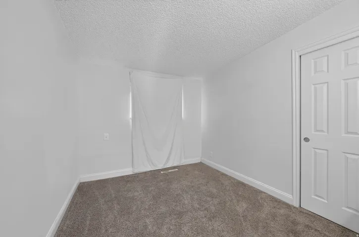 Neutral-toned wall-to-wall carpeting, white painted walls, and white baseboards create a clean interior