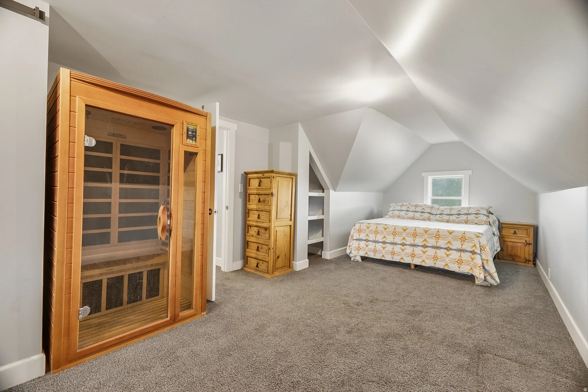 Wood-paneled sauna with glass door, recessed shelving, window, soft gray walls, and gray carpeted flooring
