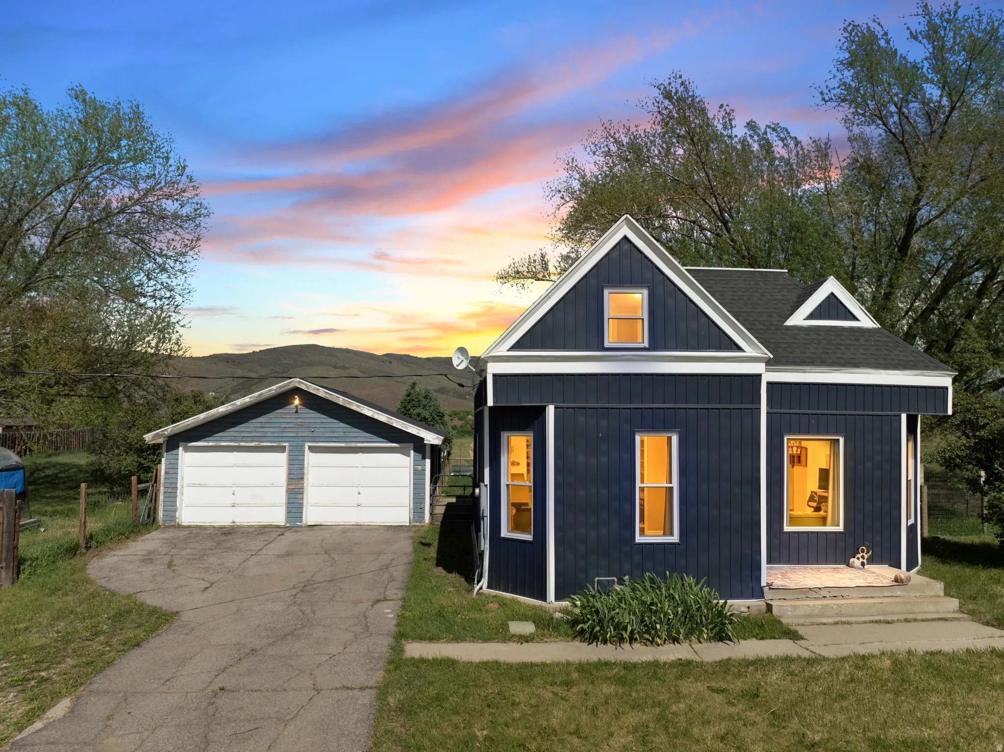 Exterior featuring dark blue vertical siding with white trim, a gabled roofline, and multiple windows