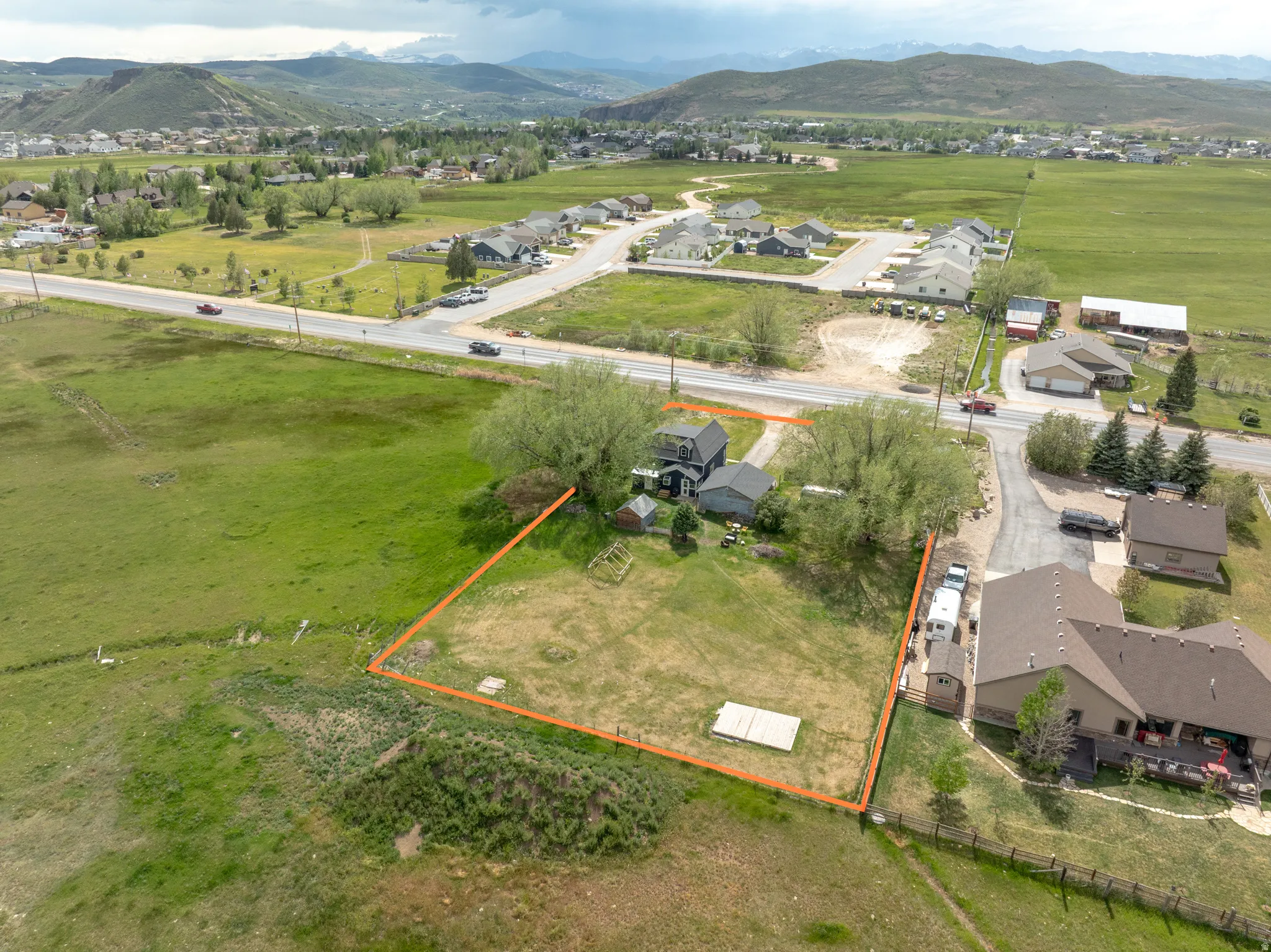 Expansive lot featuring a large grassy area, mature trees, and mountainous terrain in the background
