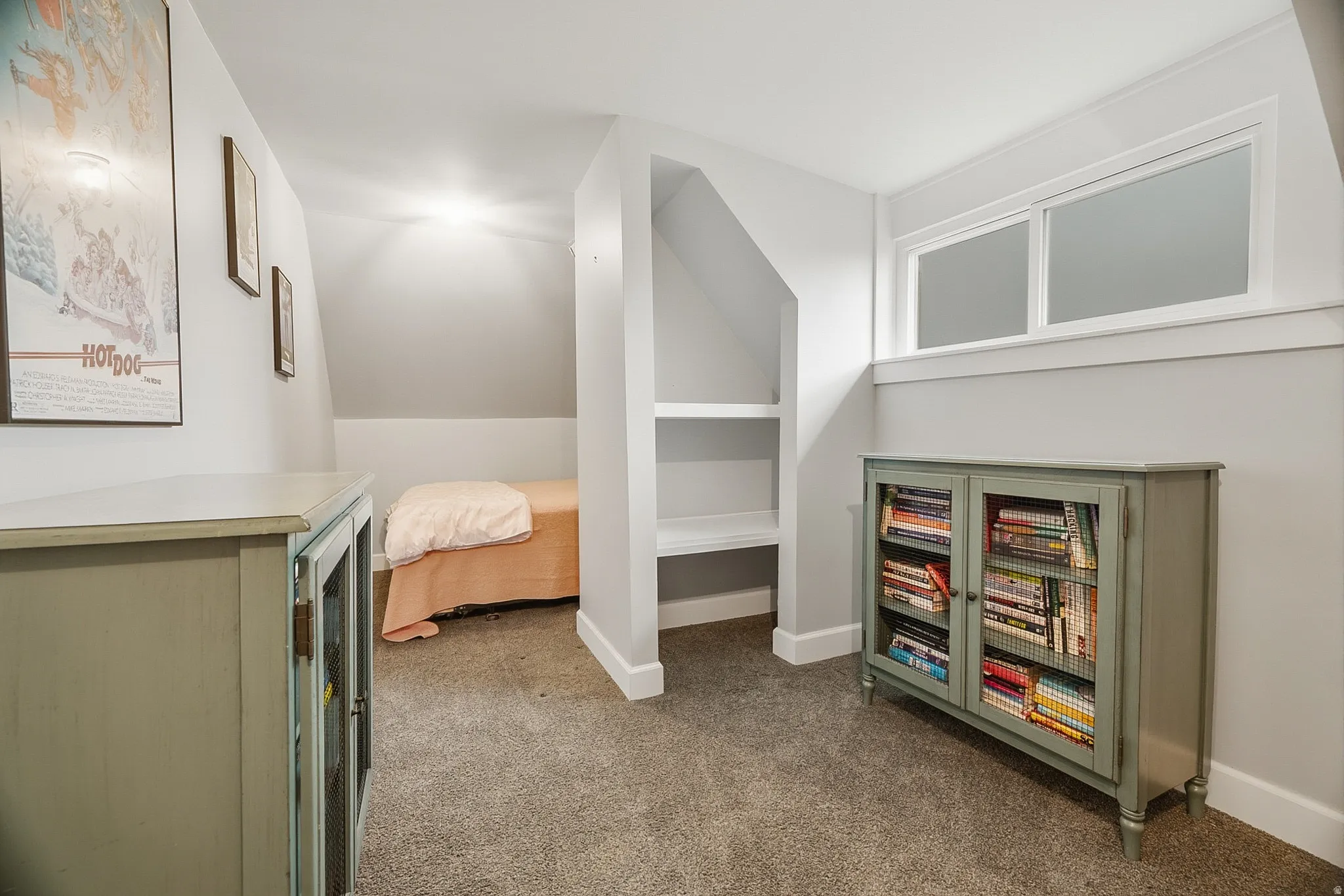 Carpeted room featuring a built-in shelving unit, a window with white trim, and light gray wall paint