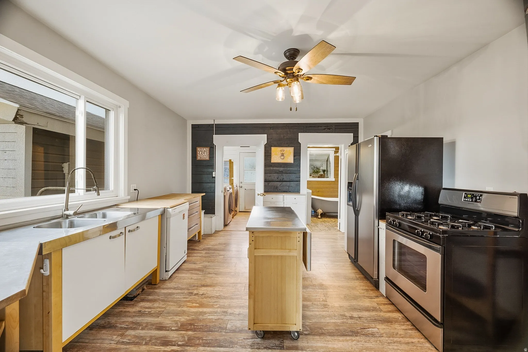 Kitchen featuring wood-finish flooring, white cabinetry, a stainless steel sink, and a four-burner range with an oven