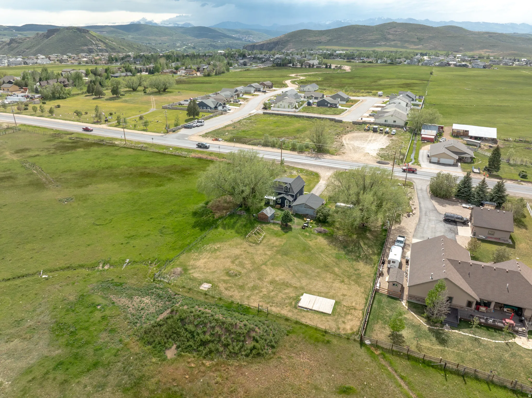 Expansive property featuring a gravel driveway, multiple outbuildings, and mature trees