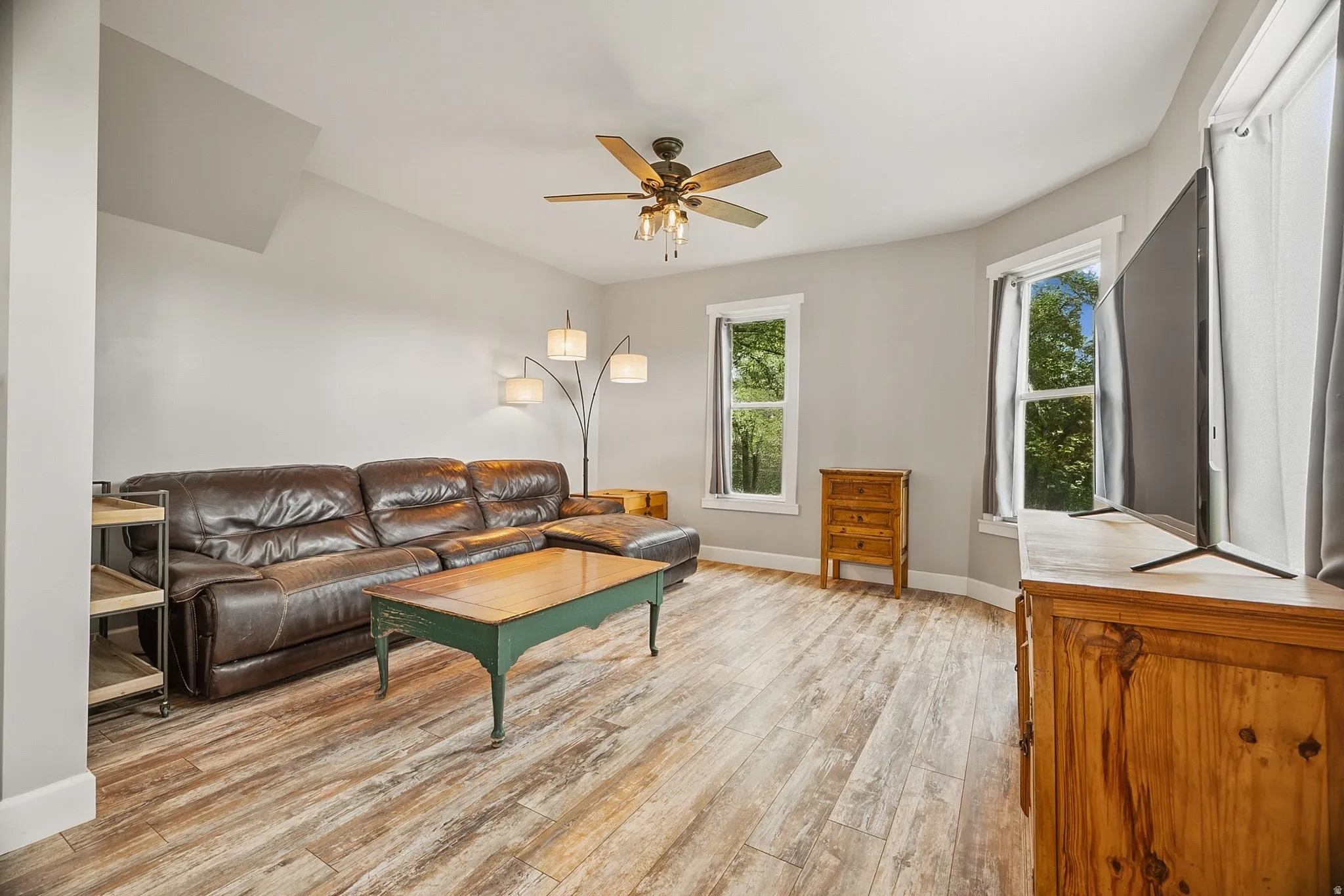 Spacious room featuring wood-finish flooring, light gray walls, and multiple windows