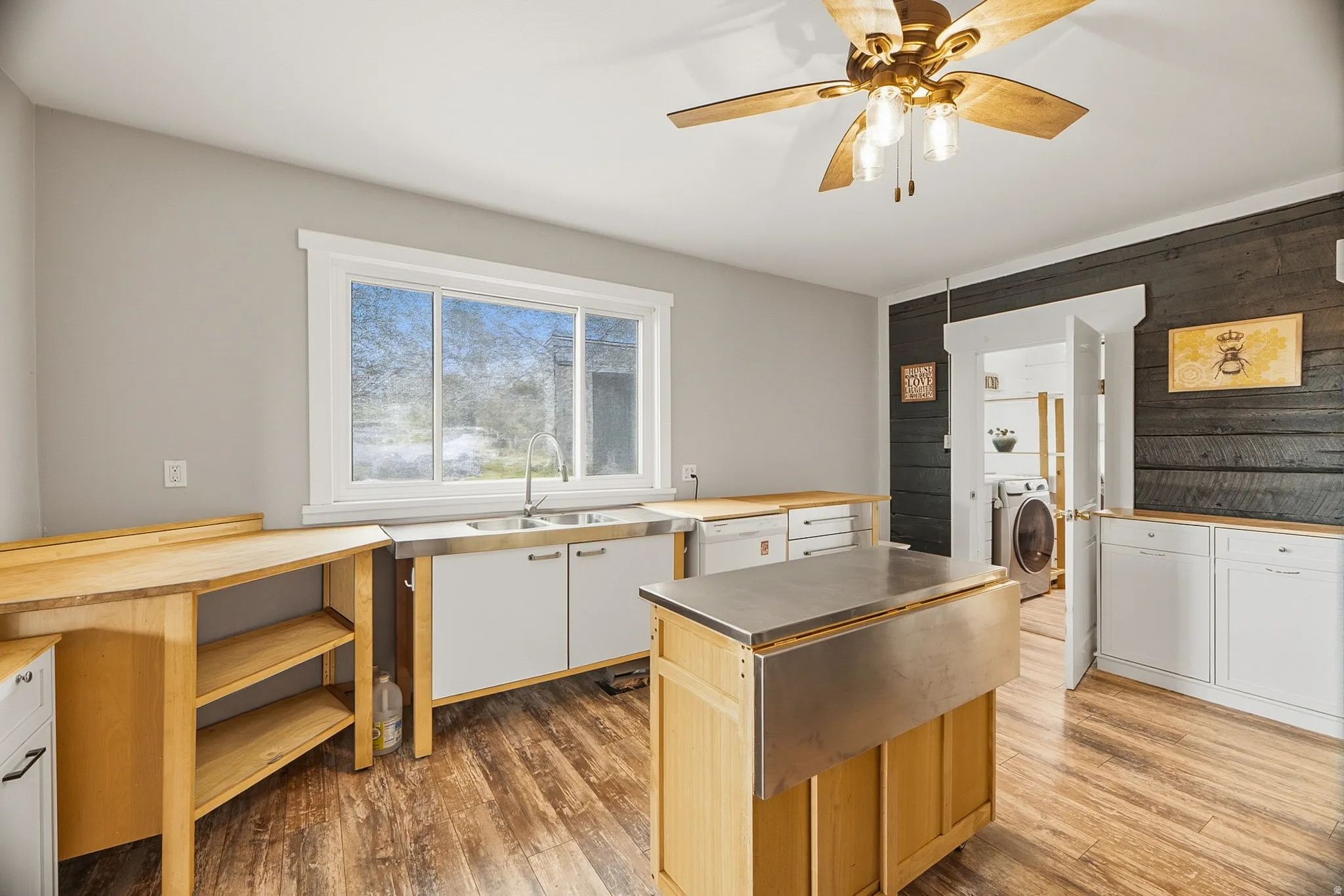 Kitchen featuring wood-finish flooring, a stainless steel sink, wood countertops, and a wood-paneled accent wall