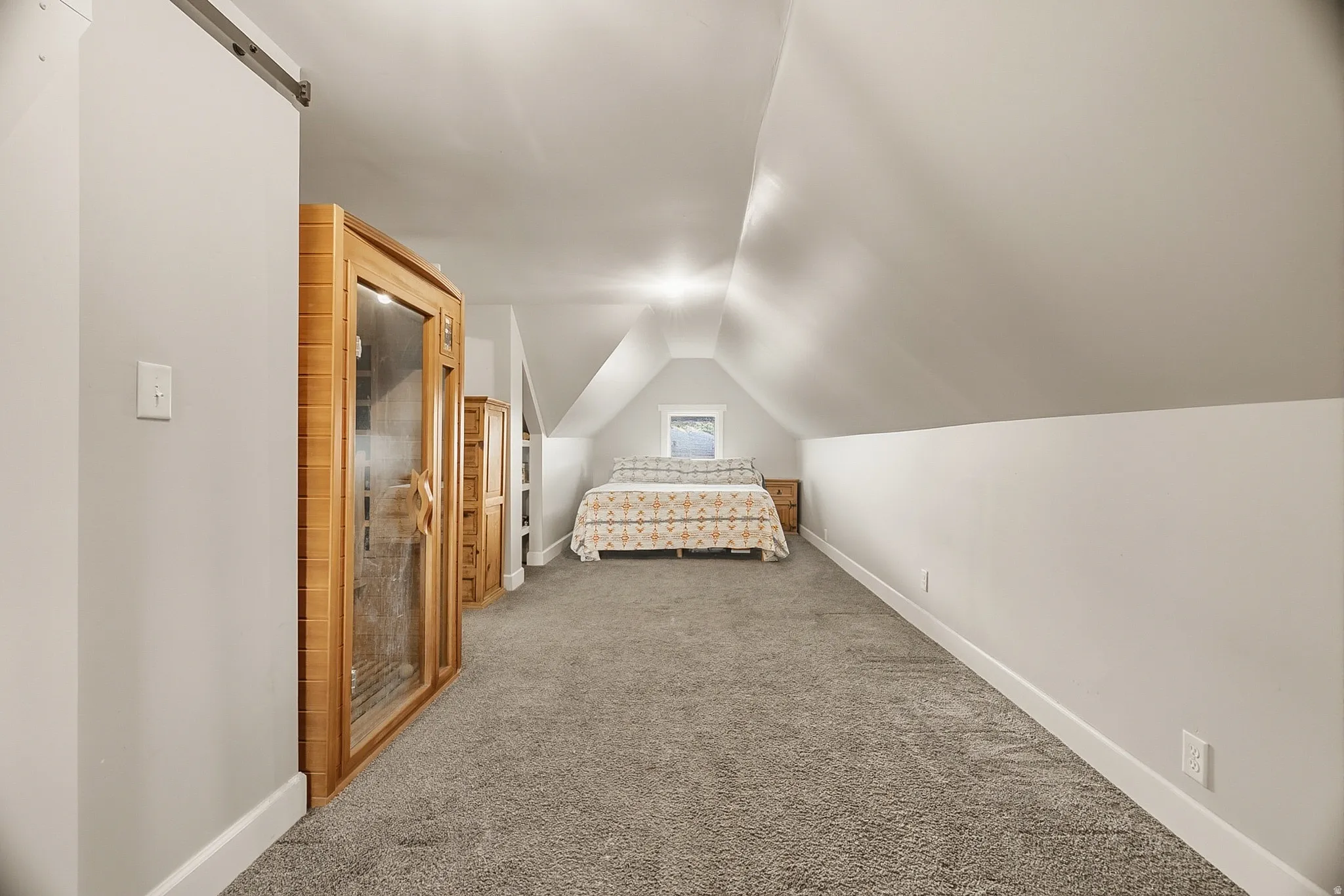 Carpeted upper-level room with sloped ceilings and recessed lighting