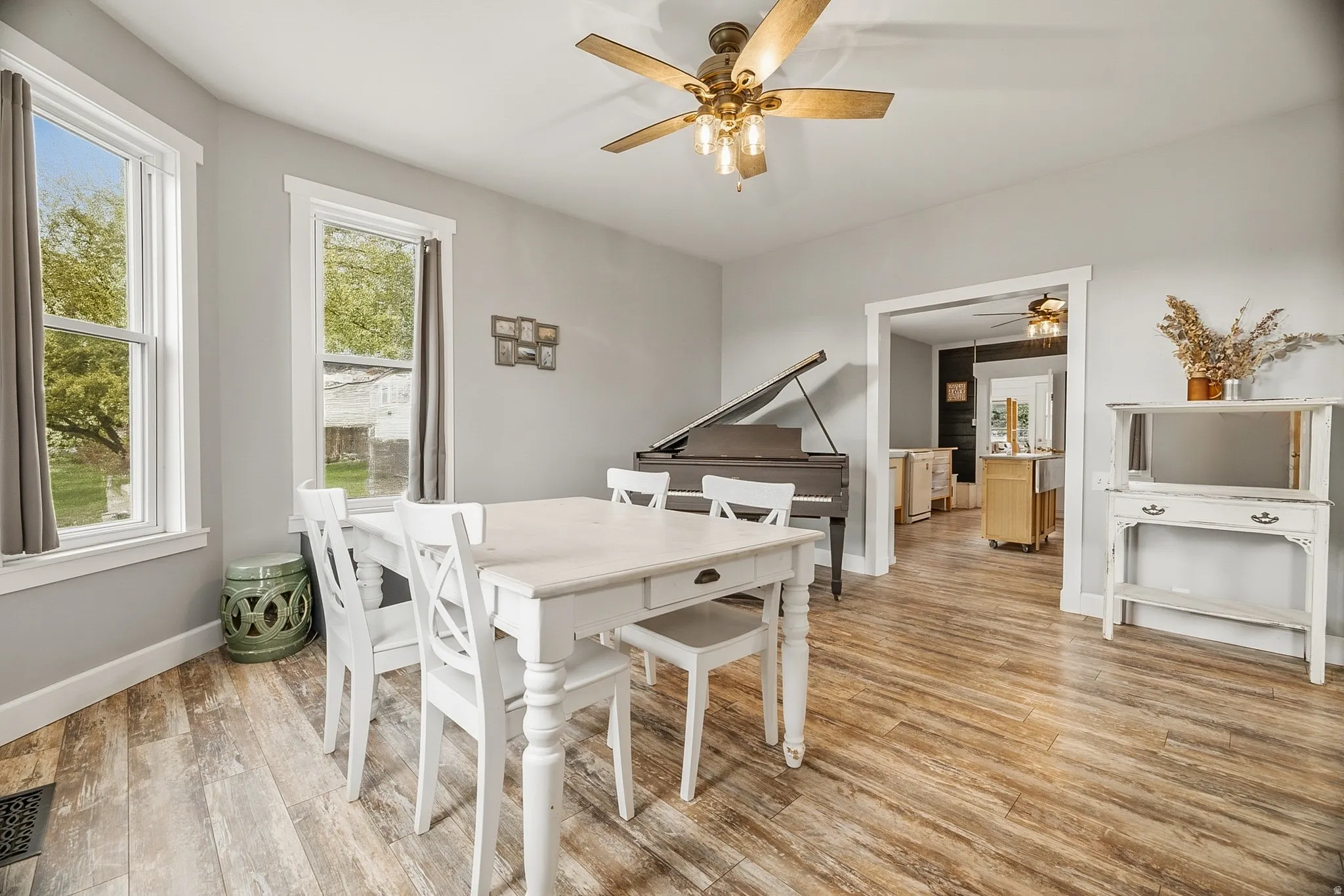 Spacious room with wood-finish flooring, two large windows, and a ceiling fan with integrated lighting