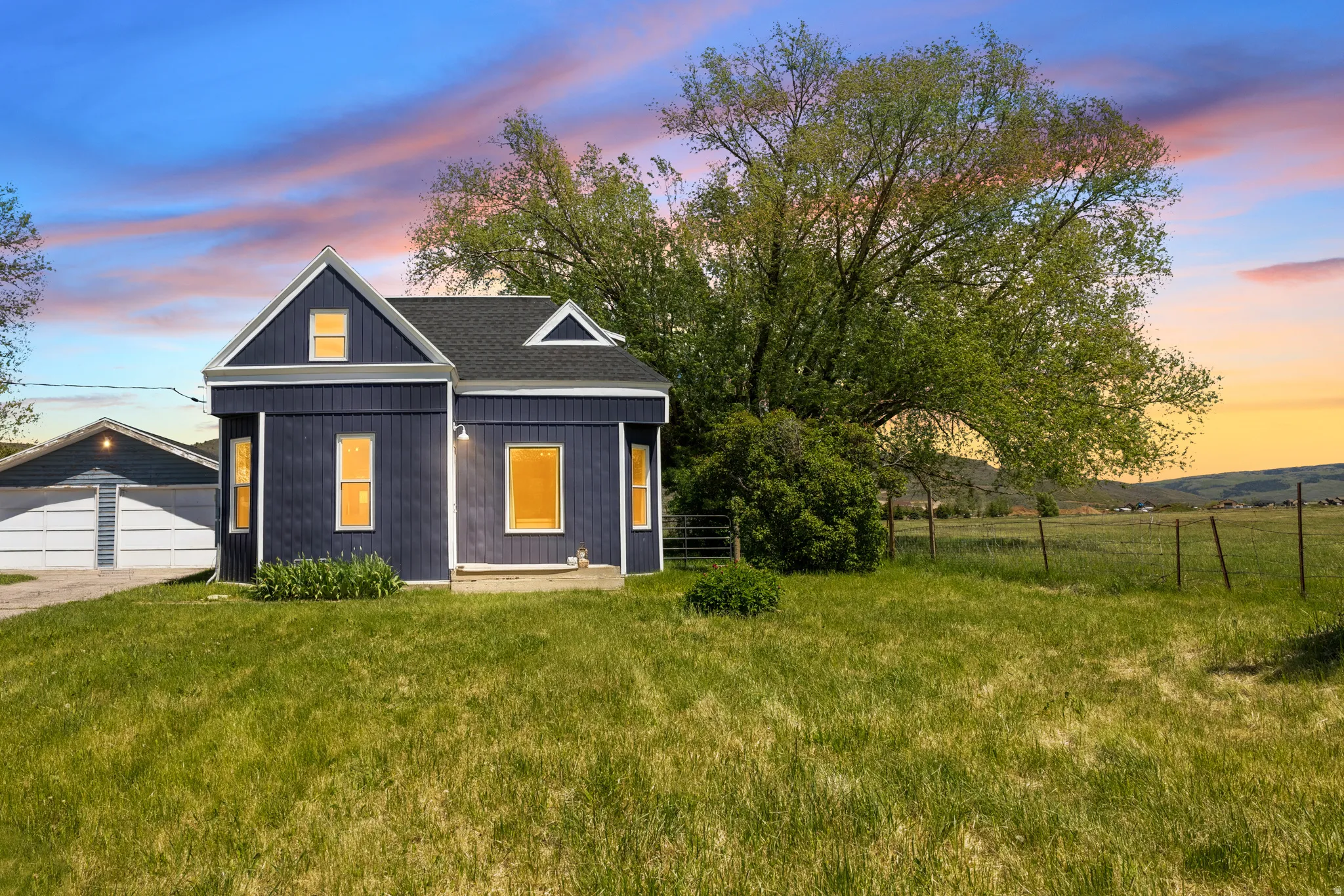 Dark blue exterior with white trim, featuring a gabled roofline and a two-car garage