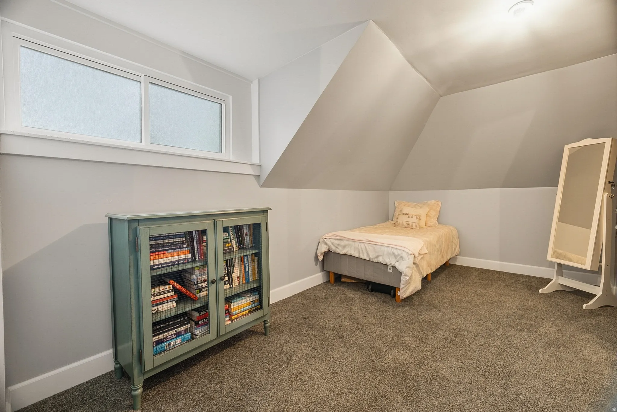 Attic room featuring a sloped ceiling, light gray wall paint, and gray carpet flooring