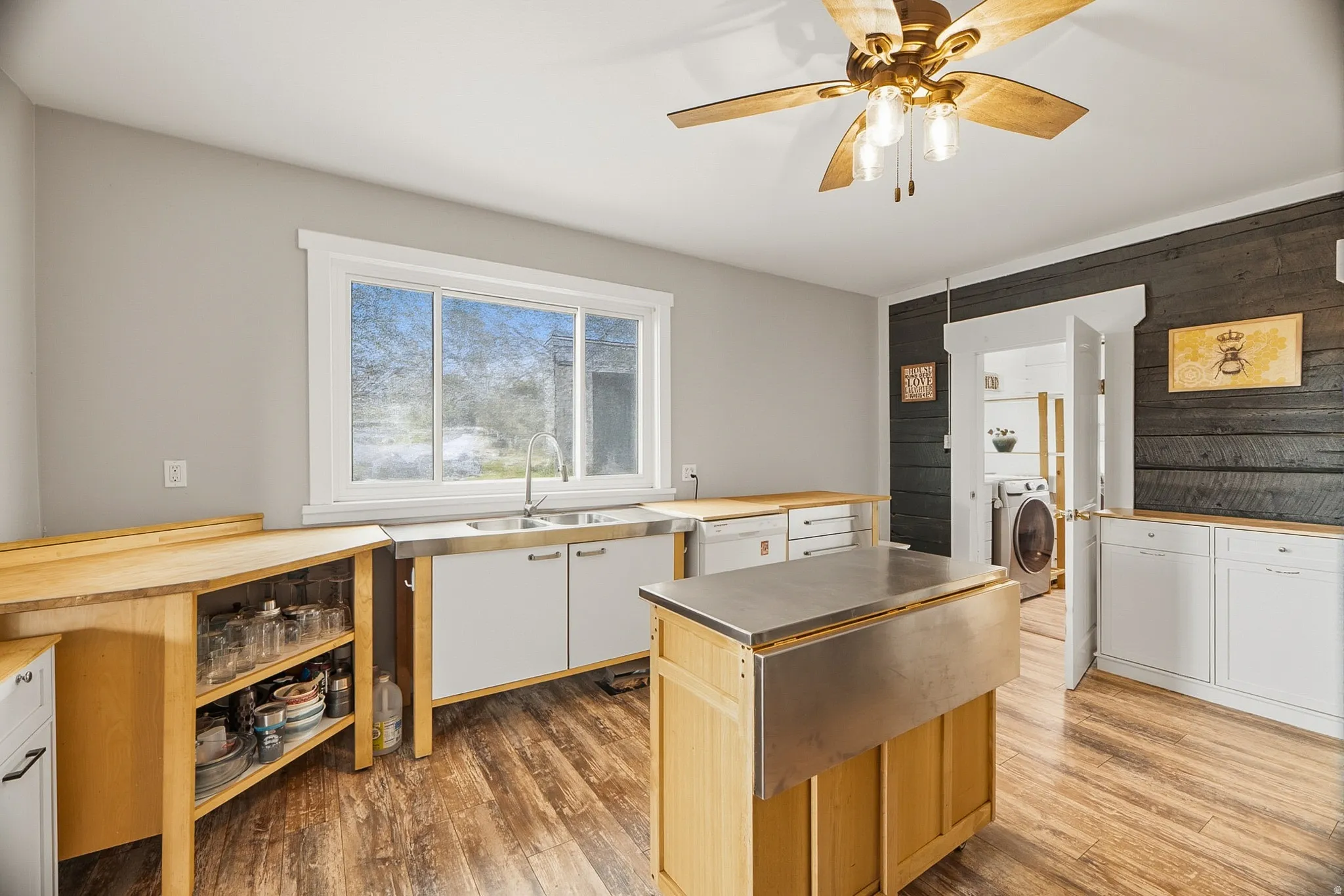 Kitchen featuring wood-finish flooring, white cabinetry, a double basin stainless steel sink, wood countertops, and a ceiling fan with light fixture