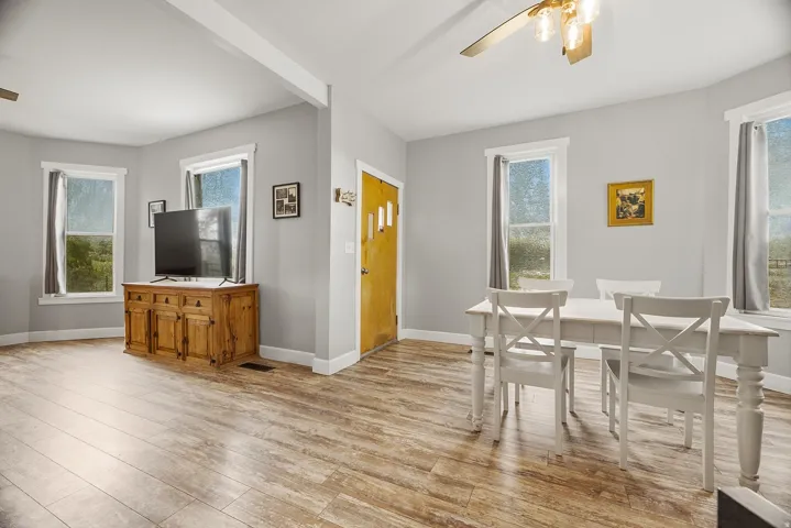 Spacious room with wood-finish flooring, light grey walls, and multiple windows