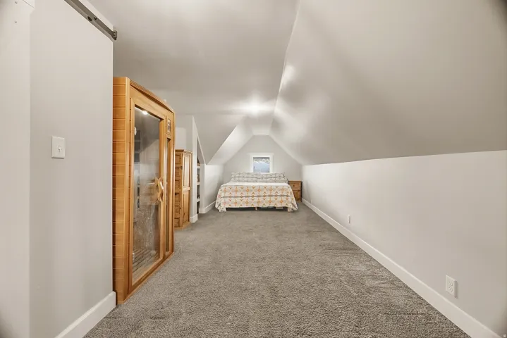Carpeted upper-level room with sloped ceilings and recessed lighting