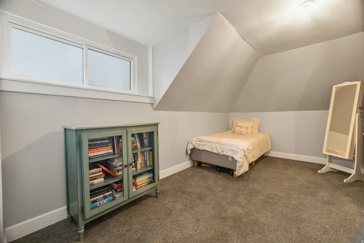 Attic room featuring a sloped ceiling, light gray wall paint, and gray carpet flooring