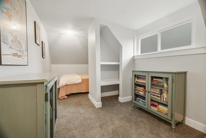 Carpeted room featuring a built-in shelving unit, a window with white trim, and light gray wall paint