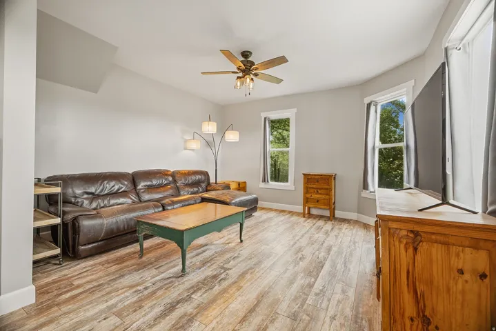 Spacious room featuring wood-finish flooring, light gray walls, and multiple windows