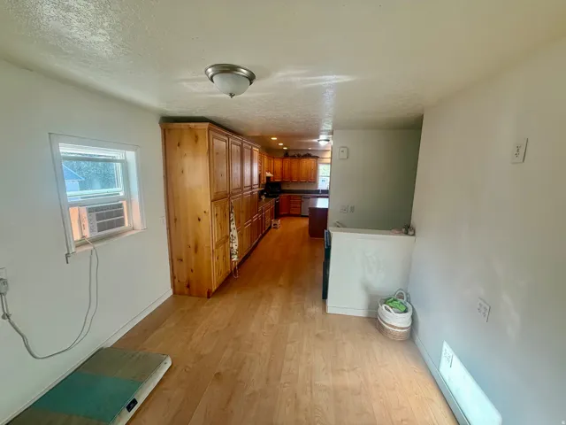 Light wood-finish flooring throughout, featuring a kitchen with extensive wood cabinetry, and a white countertop