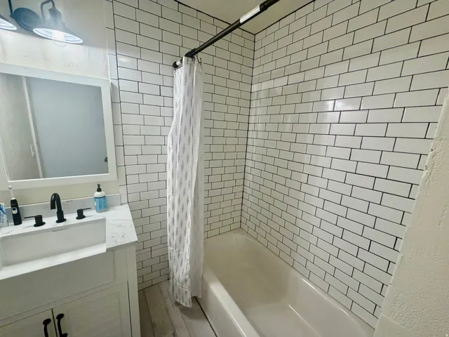 Bathroom featuring a white subway tile shower surround and a tub