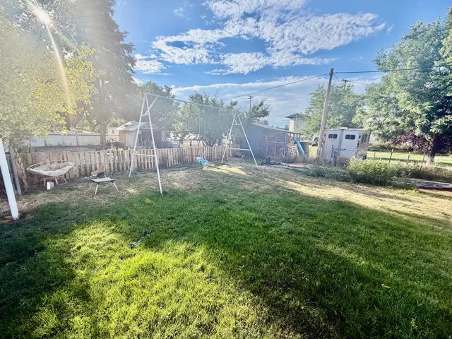 Expansive grassy yard with partial wooden fencing