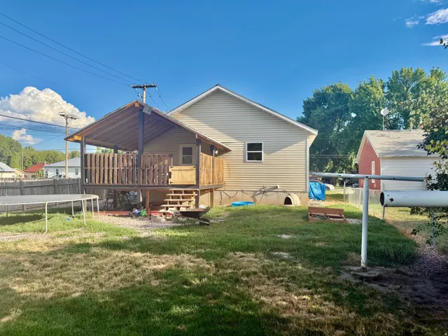 Rear exterior featuring light-colored horizontal siding and a covered wood deck