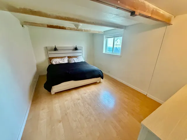 Room with exposed ceiling beams and light wood-finish flooring