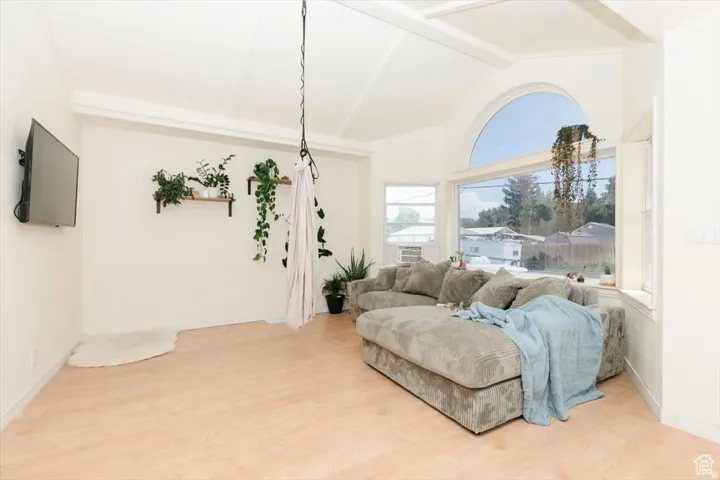 Bright living area featuring vaulted ceilings, light wood-finish flooring, and large windows including an arched transom