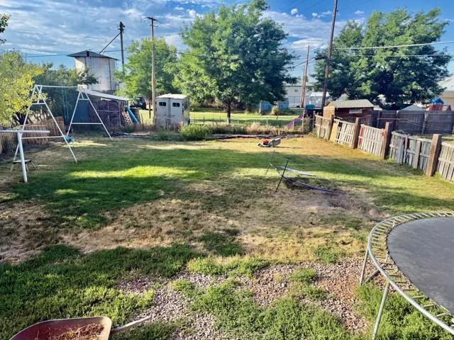 Expansive backyard featuring a combination wood and picket fence, mature trees, and a storage shed