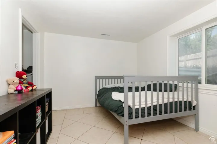 Spacious room featuring neutral white walls, tile flooring, and a large window with white trim
