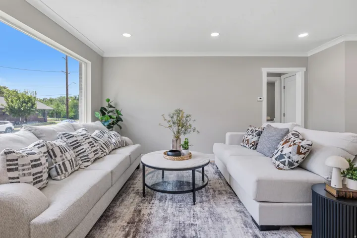 Living area featuring a large picture window, recessed lighting, crown molding, light wood-finish flooring, and a modern aesthetic