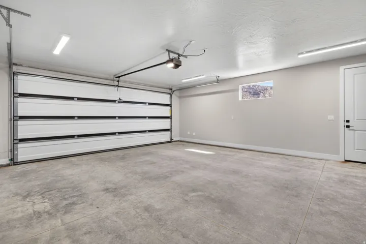 Spacious garage with a concrete floor, white sectional overhead door, and a single window