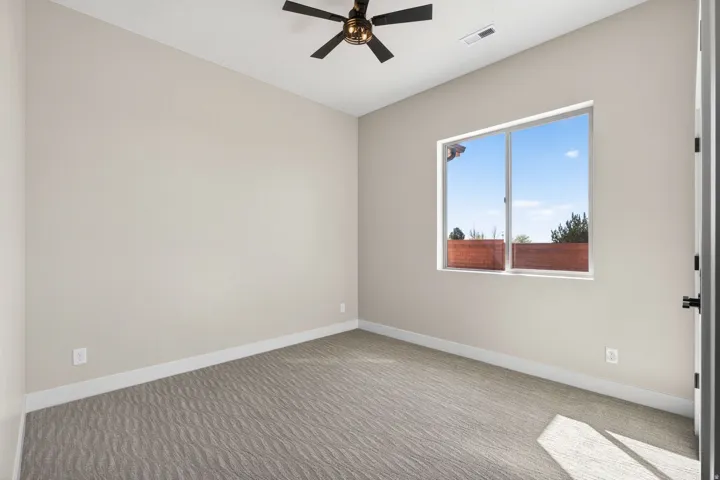 Spacious room featuring light-toned walls, patterned carpet flooring, and white trim